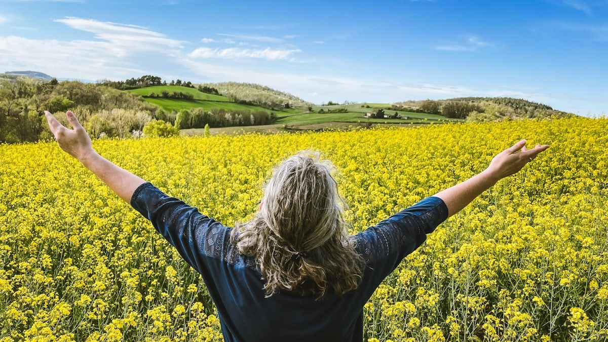 Woman embraces a field of yellow flowers